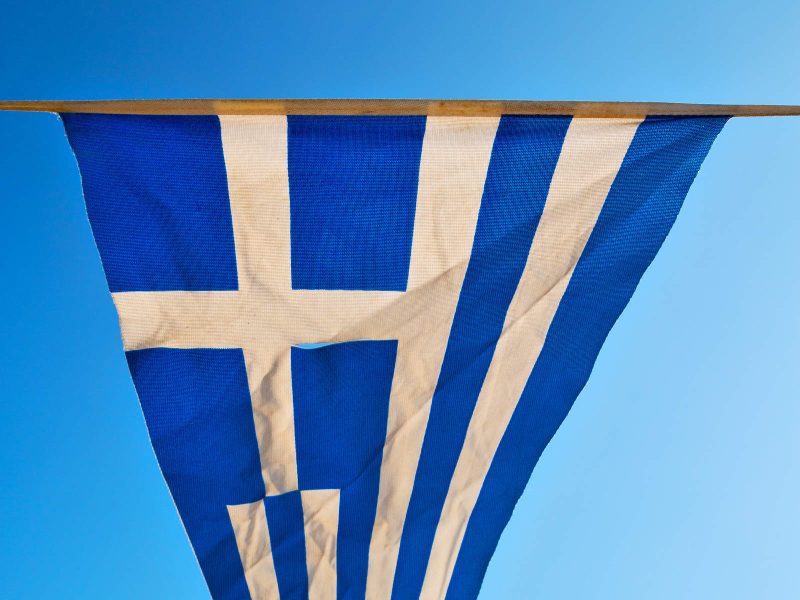 20623836_waving-greece-flag-in-the-blue-sky-and-flagpole